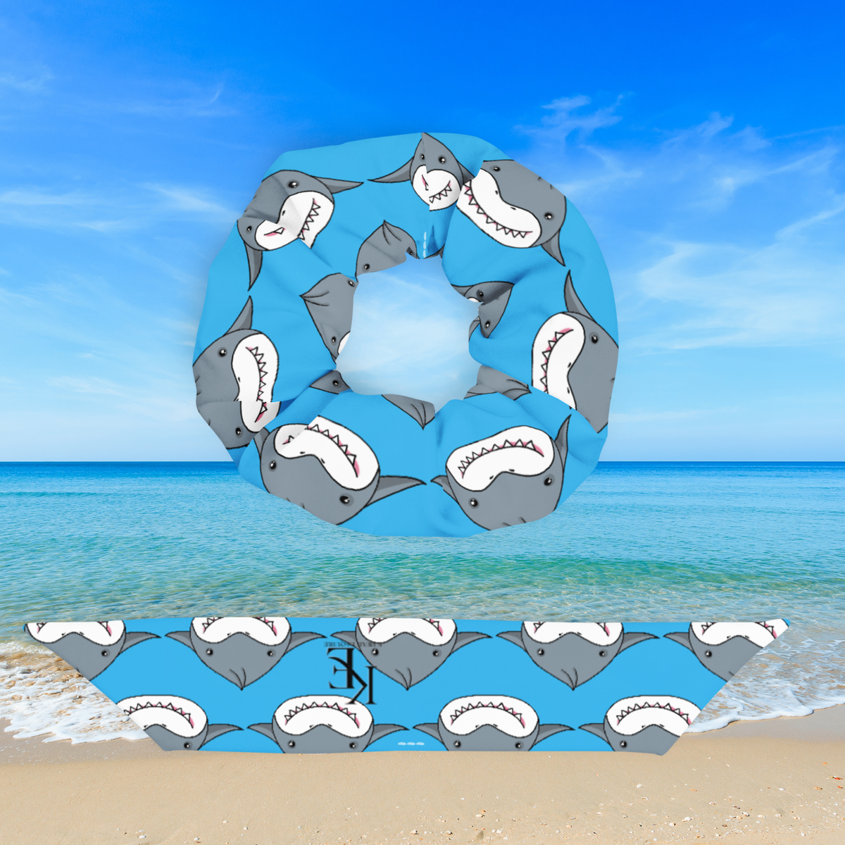Blue shark dumpling scrunchie displayed above its detached matching bow, showing the repeating gray-and-white shark pattern against an ocean backdrop.