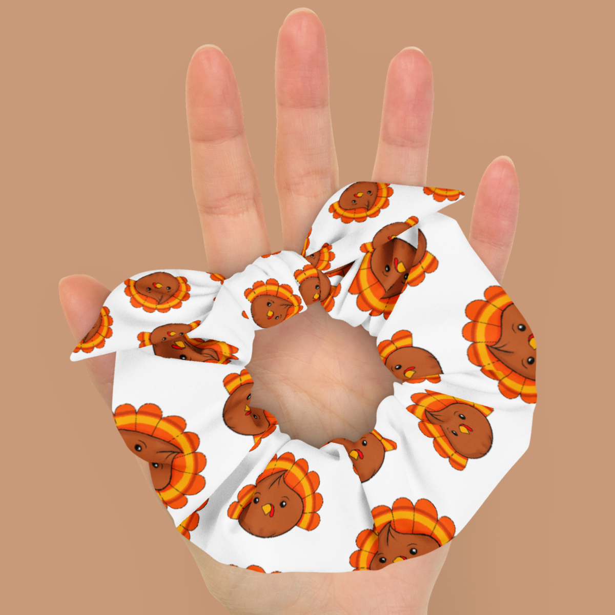 Close-up of a turkey dumpling scrunchie and tied matching bow held in an open hand, showing the gathered white fabric and colorful print.