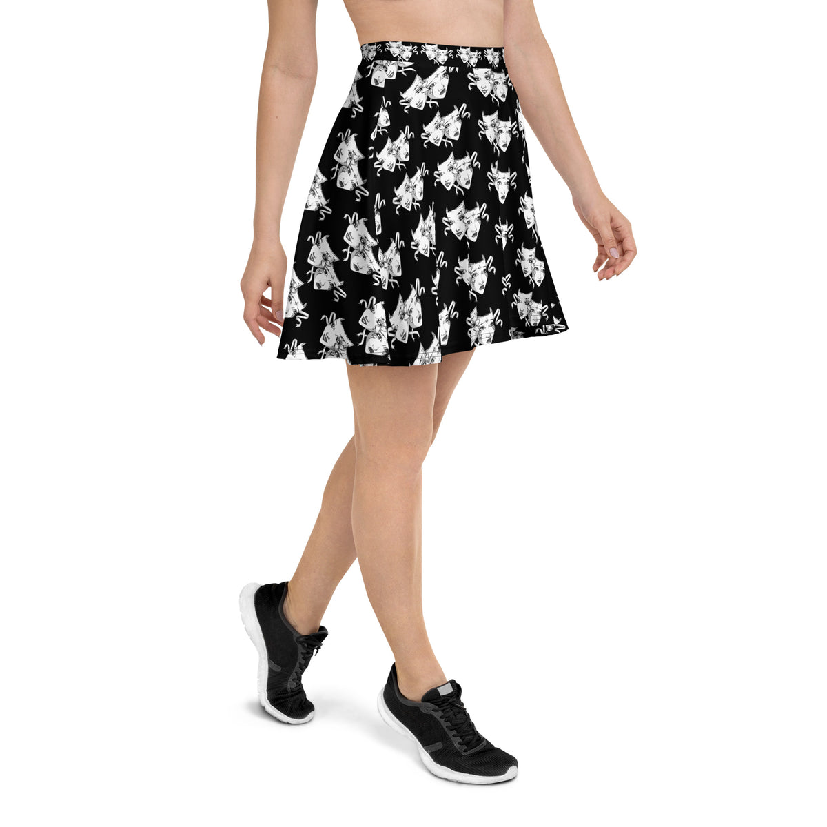 Model walking in a black skater skirt featuring white illustrated comedy and tragedy mask pattern. Lightweight, flowy design ideal for dramatic and theatrical fashion lovers.