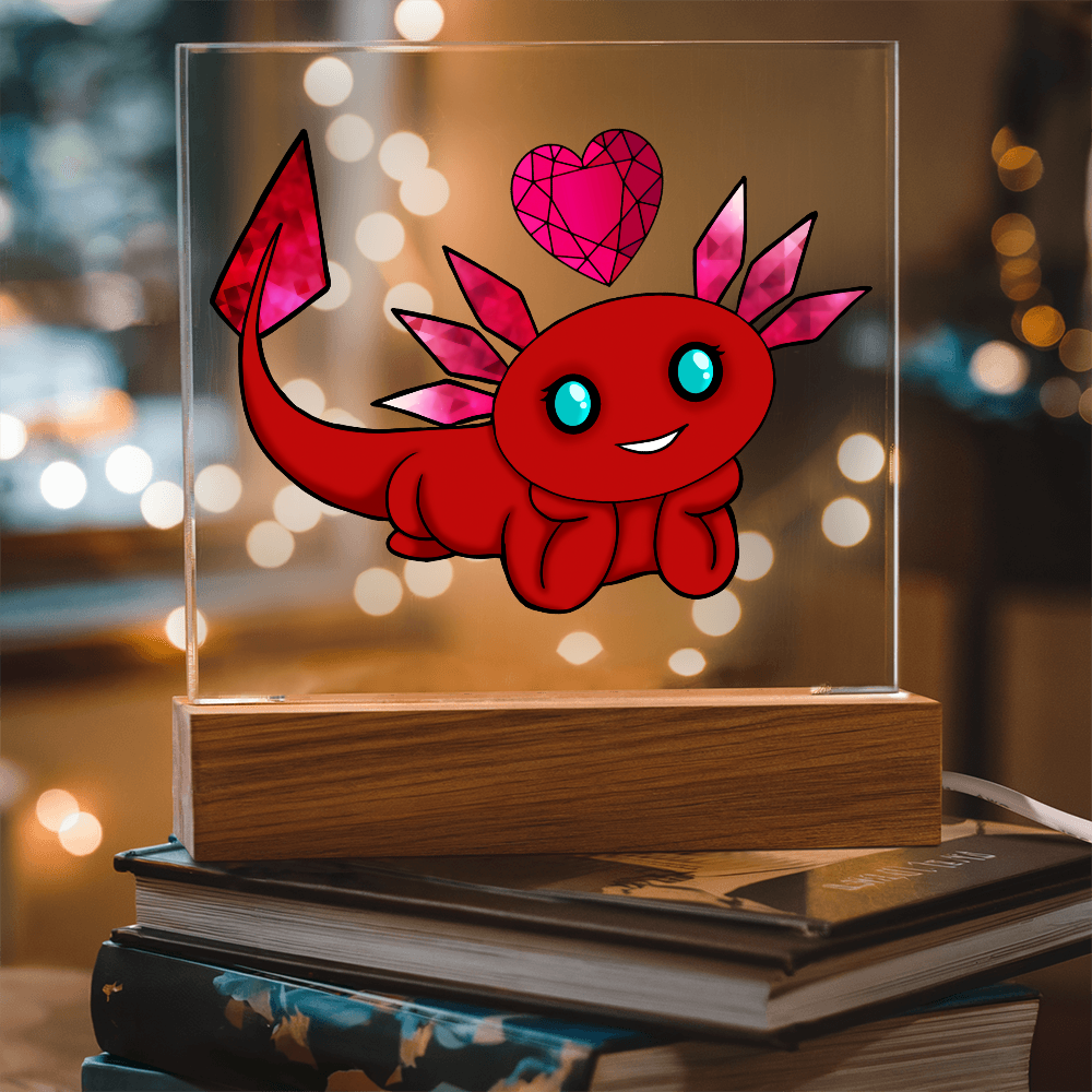 January birthstone axolotl acrylic plaque with red and pink gemstone details displayed on stacked books