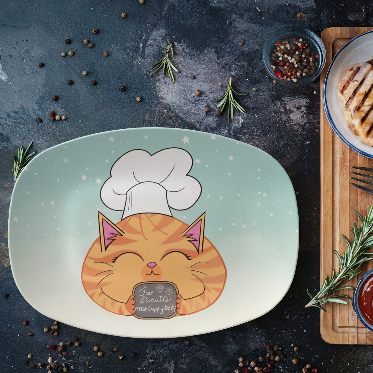 Cat serving platter with orange tabby chef design styled on a table beside food and cooking herbs